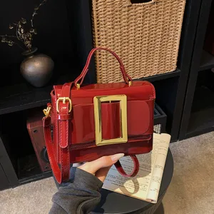 Trendy glossy red retro shoulder bag with large gold buckle and chic top handle for women.