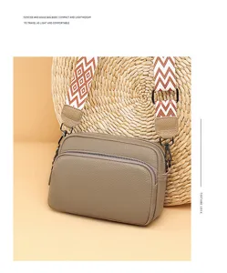 Detail view of the elegant khaki leather crossbody bag with patterned strap and metal zipper.
