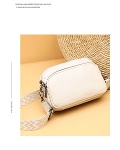 Beige litchi texture leather crossbody bag detail, compact square bag with ethnic pattern strap.