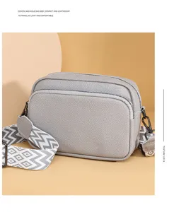Women's minimalist pebbled leather crossbody bag with wide geometric strap and dual zip.