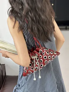 Red patent leather shoulder handbag with metal grommets and pearl chain for women.