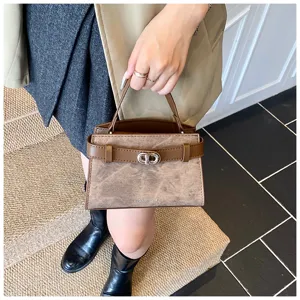 Stylish brown top handle bag detail featuring elegant belt strap and metal turn-lock closure.