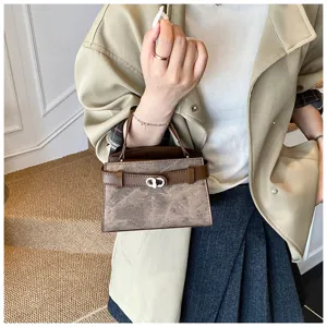 Detail view of stylish leather handbag with metal turn-lock clasp and top handle design.