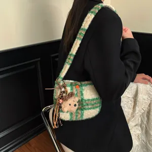 Close-up detail of a vintage green plaid lamb wool crossbody bag featuring a cute bear pendant.