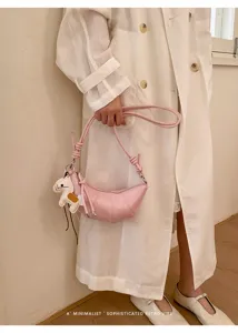 Close-up view of trendy pink croissant crossbody bag showcasing stylish knot and charm detail.