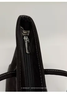 Close-up detail of black suede tote bag zipper, minimalist retro style and metal hardware.