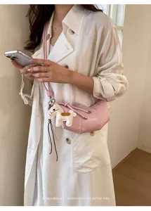Stylish pink croissant dumpling crossbody bag with cute leather horse charm for women.