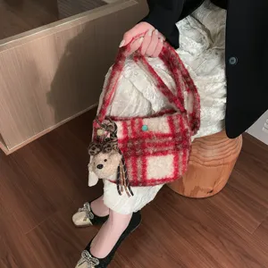 Close-up detail of retro red plaid lamb wool crossbody handbag featuring cute plush bear pendant.