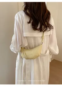 Detail view of stylish yellow leather croissant crossbody bag with unique knotted strap design.