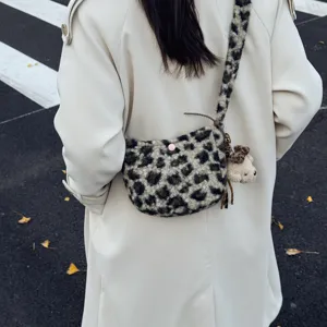 Detail shot of a fuzzy leopard print crossbody bag with cute bear charm for women.