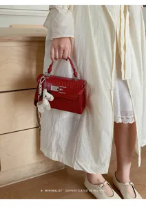 Red crocodile textured handbag detail featuring premium metal lock and a cute horse charm.