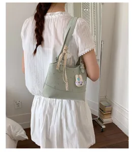 Chic green shoulder bag for women with cute lace ribbon and bunny pendant daily commute style.