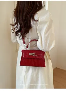 Detailed view of a red crocodile pattern leather handbag with metallic lock, elegant and chic.