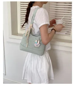 Korean style light green shoulder bag detail shot with cute rabbit pendant and lace ribbon.