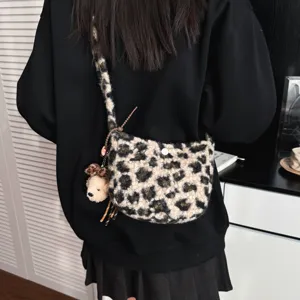 Detail shot of fluffy leopard print crossbody bag with cute bear pendant and lamb wool texture.
