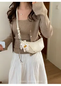 Minimalist white crescent croissant crossbody bag detail view with chic horse charm accent