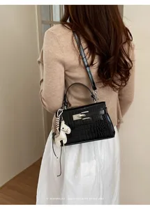 Close-up detail of the elegant black crocodile pattern handbag with metal lock and cute charm.