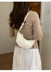 Detail view of stylish white leather croissant dumpling shoulder bag for women daily commute.