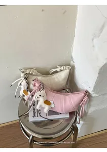Detailed shot of trendy minimalist croissant crossbody bag with cute horse charm and retro vibe.