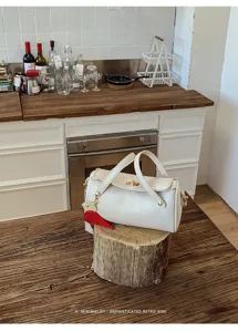 Borsa a tracolla cilindrica bianca minimalista con serratura in metallo per donne.
