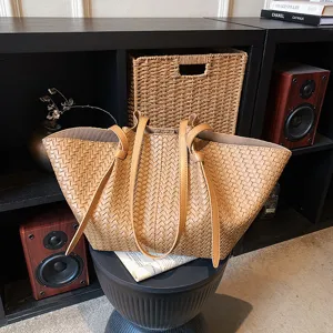 Close-up of brown woven leather tote bag on black stool, highlighting premium texture.