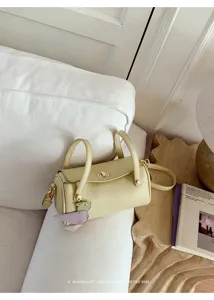 Borsa a tracolla cilindrica verde chiaro minimalista con manico elegante e ciondolo.