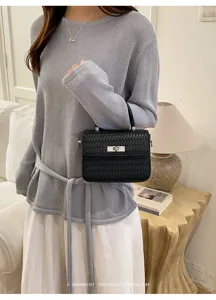 Vista detallada del elegante bolso de hombro negro tejido, con textura y estilo chic.