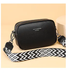 Black leather camera crossbody bag with wide geometric strap, fashion multi-layer shoulder bag.