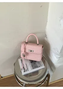 Vista detallada de un bolso de mano tejido rosa en taburete de metal con revista.