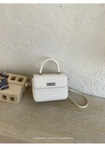 Vista de primer plano detallada del elegante bolso blanco tejido con cierre giratorio.