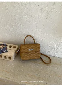 Primer plano detallado del elegante bolso cruzado mini marrón tejido con cierre metálico elegante.