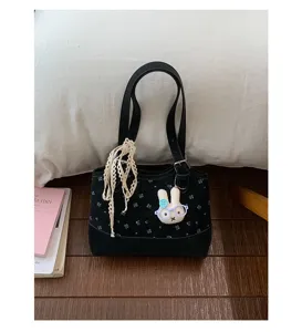 Detailed view of black canvas shoulder bag with cute rabbit pendant and lace ribbon decoration.