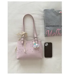 Detailed shot of chic pink shoulder bag with floral print, cute rabbit charm and lace bow.