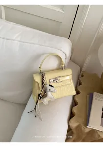 Yellow crocodile textured leather Kelly handbag detail, elegant top handle retro style.