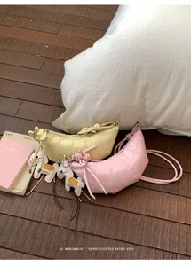 Detailed shot of trendy minimalist croissant shoulder bag with cute horse charm in daily scene.