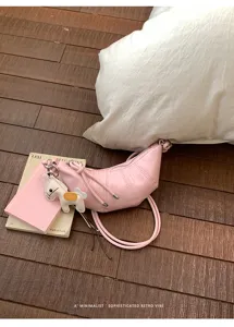 Pink croissant crossbody bag detail view featuring a cute horse charm and retro vibe.