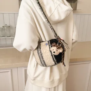 Detail view of a cozy winter lamb wool plaid crossbody bag with cute bear charm worn by model.