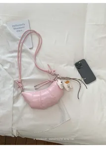 Detail view of the pink PU leather croissant crossbody bag with cute horse charm accessory.