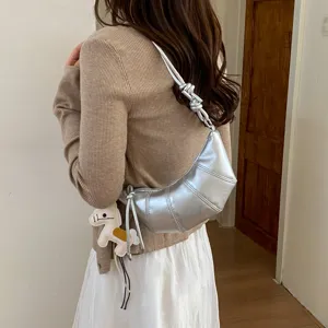 Metallic silver croissant shoulder bag with knotted strap and chic style for daily commute.