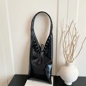Detail view of vintage black leather hobo shoulder bag with metal eyelet and strap design.