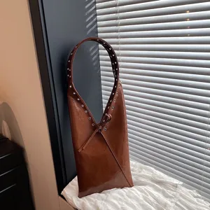 Detailed shot of retro brown crinkled leather shoulder bag with metal grommets and strap tie.