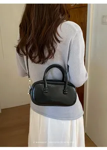 Vue de détail du sac à main bowling noir en cuir élégant porté à l'épaule style rétro.