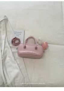 Détail de sac à main bowling en cuir rose, avec poignées courtes, bandoulière et joli pendentif.