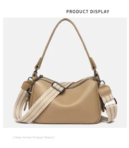 Detailed closeup of khaki leather crossbody bag with wide patterned strap and metal hardware.