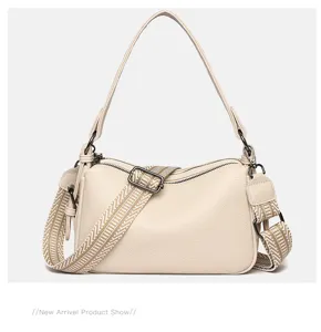 Textured genuine leather shoulder bag detail with wide woven strap and double zipper.