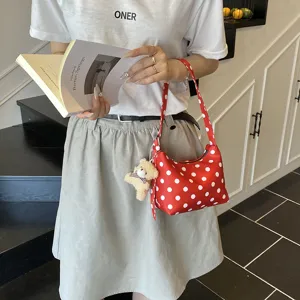 Red polka dot shoulder bag for women, stylish underarm handbag with cute bear charm.