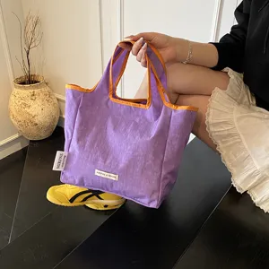 Detailed view of casual purple canvas tote bag with vibrant orange trim, portable and stylish.
