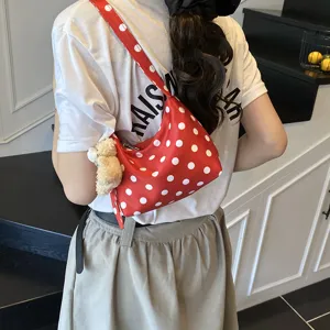 Detail shot of trendy red polka dot underarm shoulder bag with cute plush bear pendant.