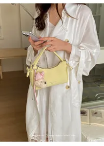 Elegant yellow leather handbag for women, chic commuting small shoulder bag with cute plush charm.
