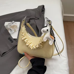 Stylish yellow shoulder bag for women, featuring pleated strap and cute horse charm.